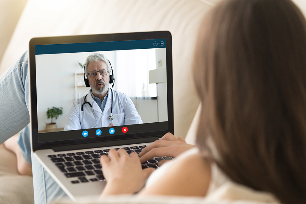 Girl communicating distantly with doctor using webcamera and laptop Girl communicating remotely with doctor