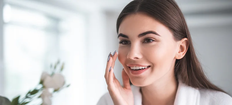 Smiling Woman Applying Moisturizer
